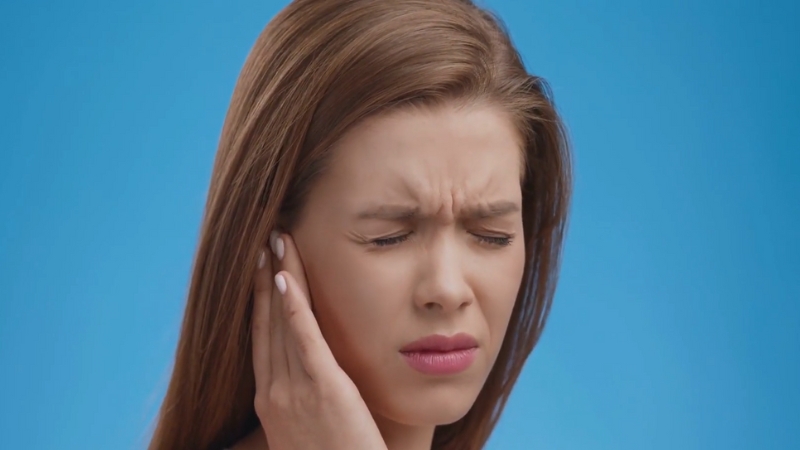 A Woman Is Holding Her Ear in Pain, Potentially Due to Wisdom Teeth Discomfort