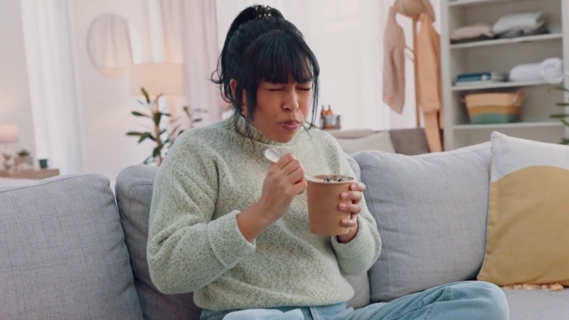 A Person Sitting on A Couch Experiencing Brain Freeze While Eating Ice Cream