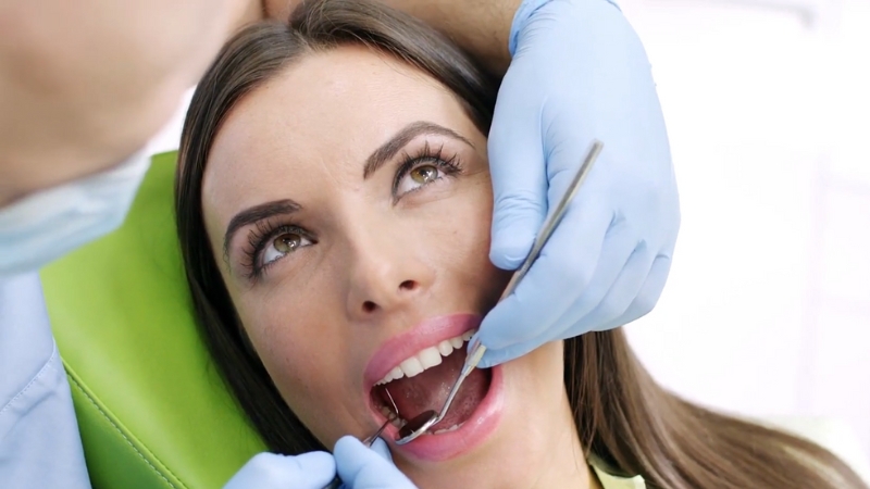 A Woman Is Receiving a Dental Checkup from A Professional